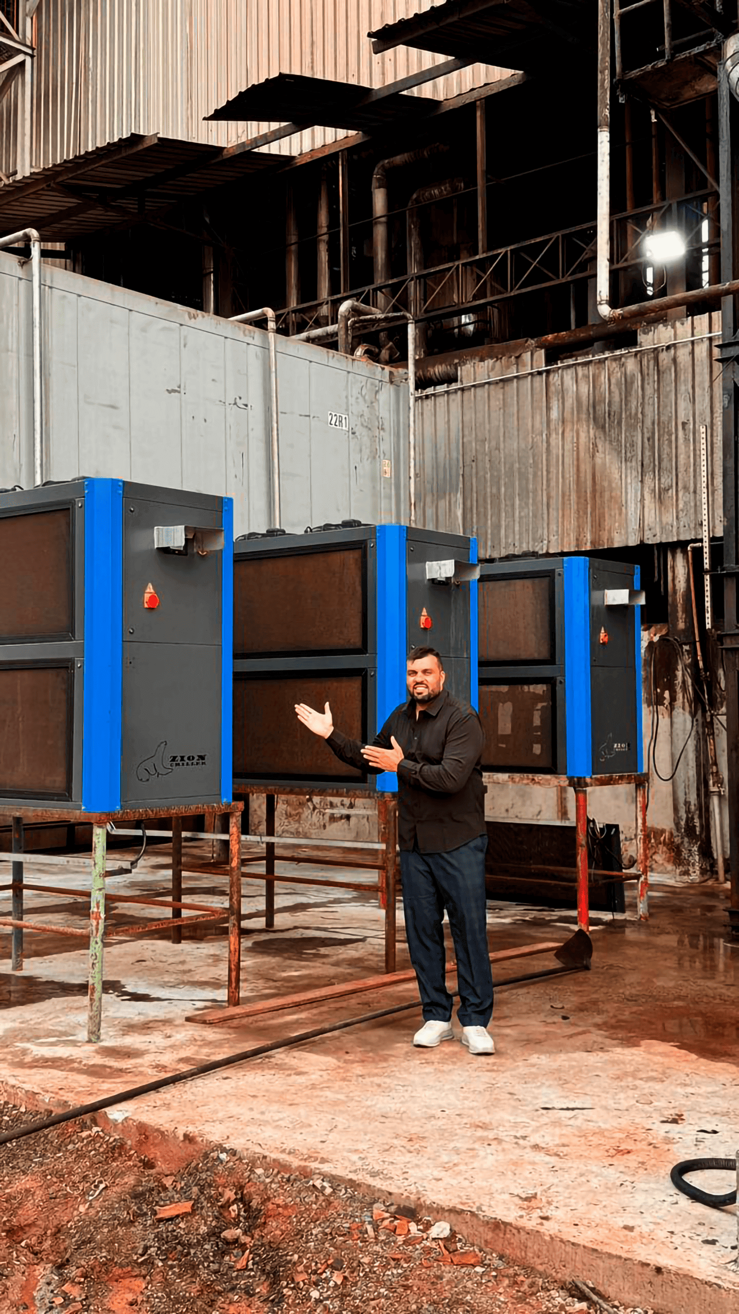 Várias grandes máquinas industriais azuis e marrons com um especialista apontando para elas